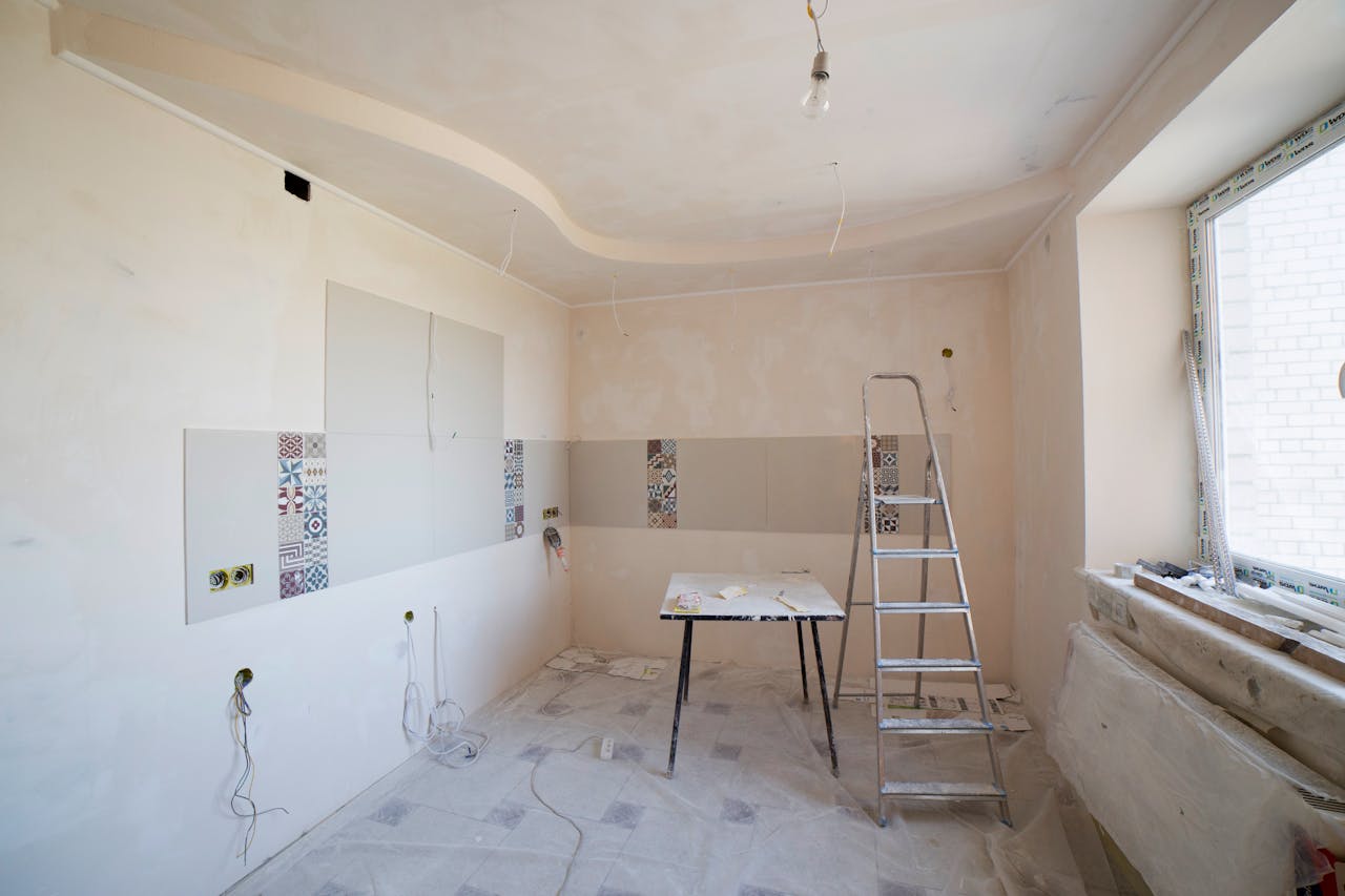 Spacious kitchen under renovation with ladder and tools, showcasing a fresh new design.